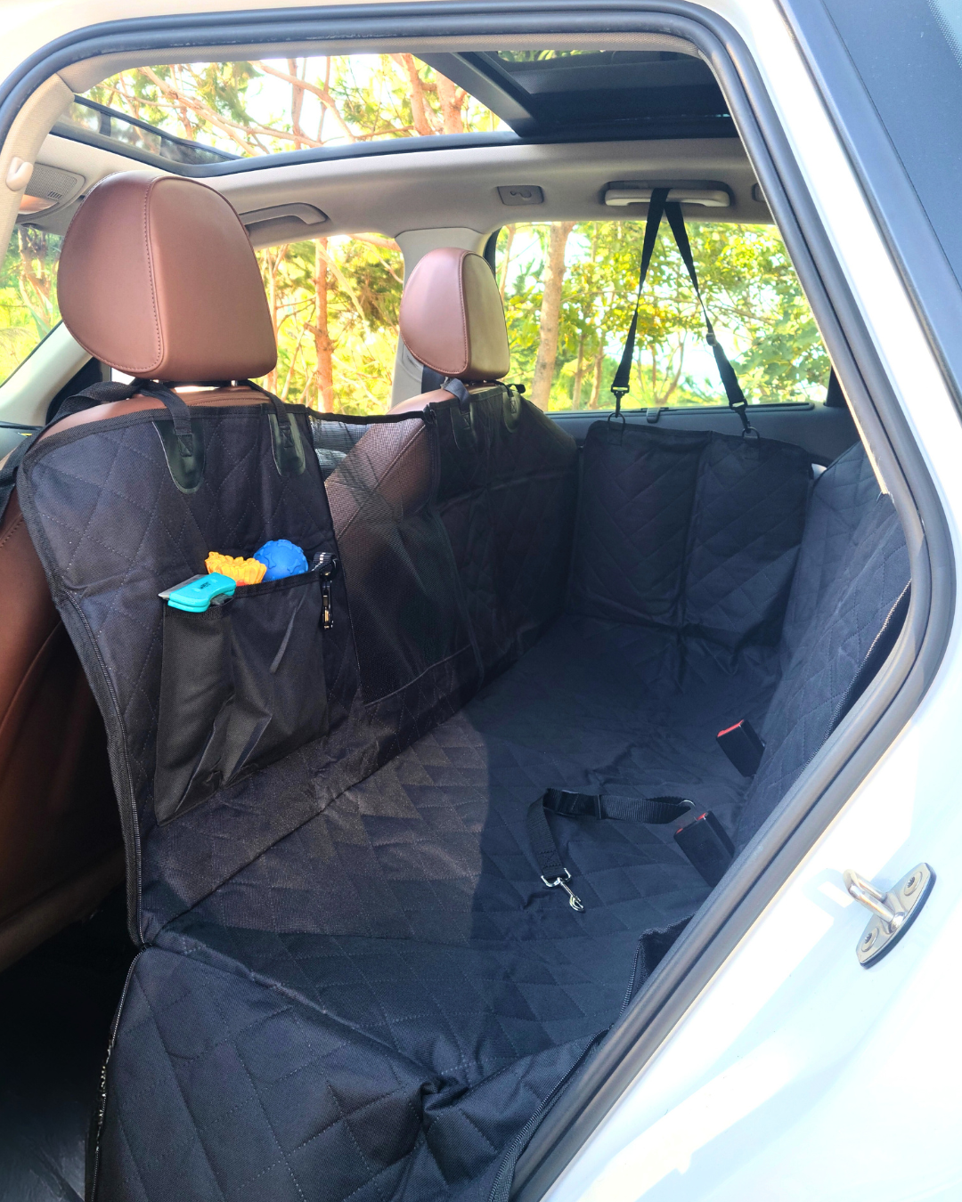Normal dog backseat cover installed in the backseat of a car with items in the pockets and a visible seatbelt opening